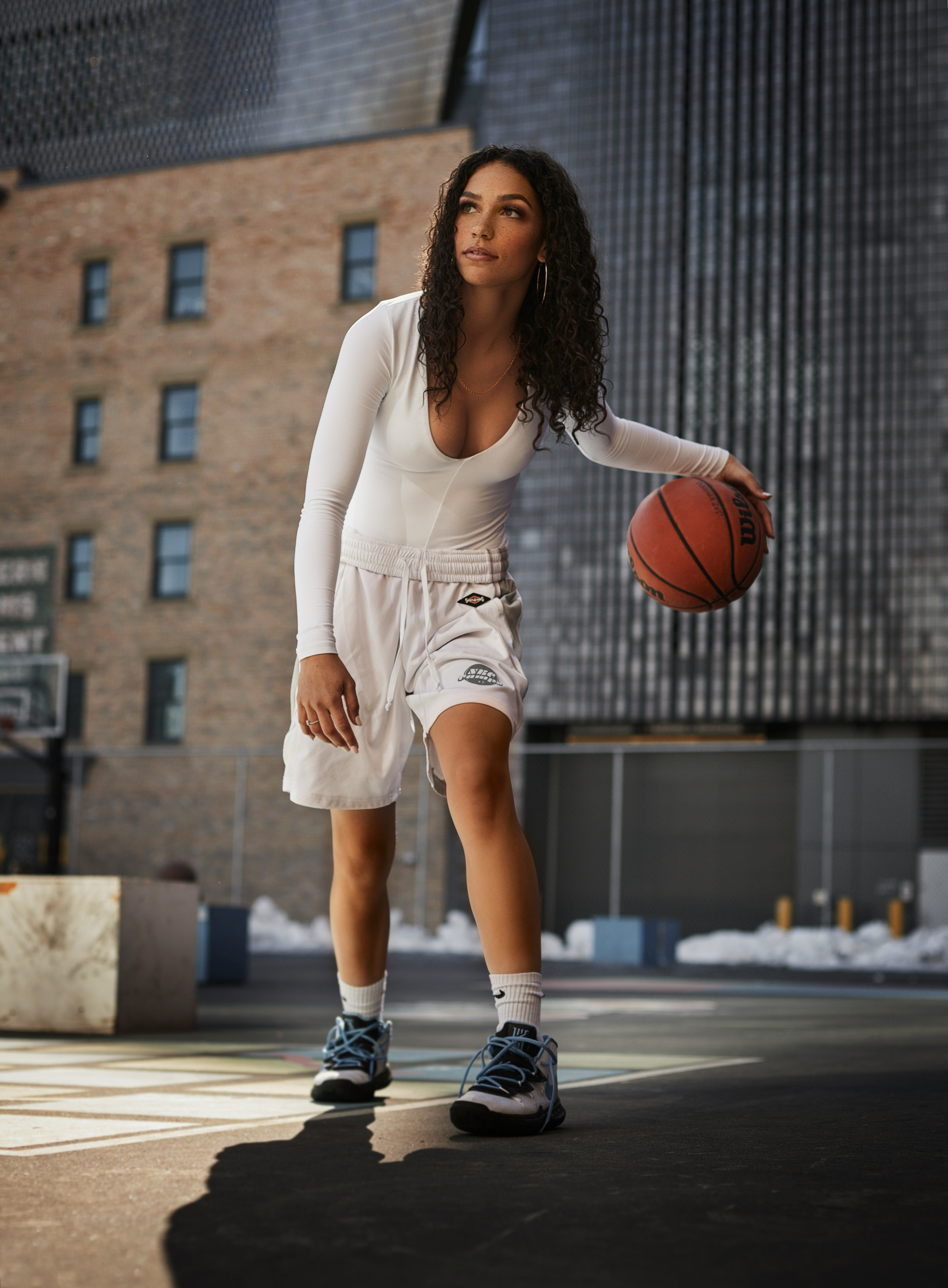 woman in white tank top and white shorts holding basketball